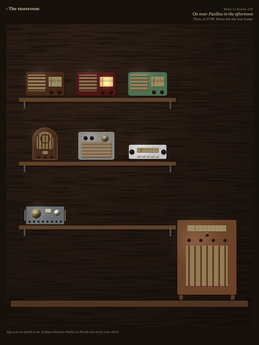The shelf: eight restored radios on wooden planks and a console on the floor, one maroon table set with its dial lit