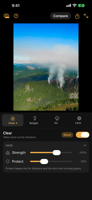 Clear on a mountain forest with smoke rising from it: the haze taken out, so the far ridges and the sky are crisp